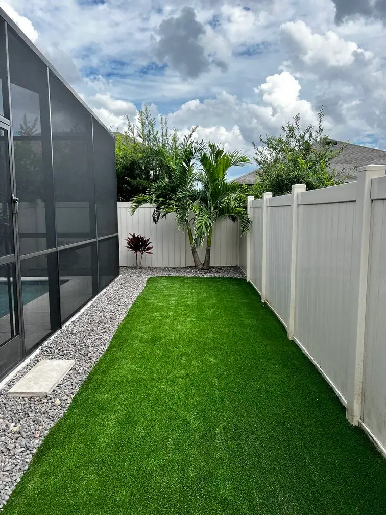 Backyard with artificial turf and palm trees.